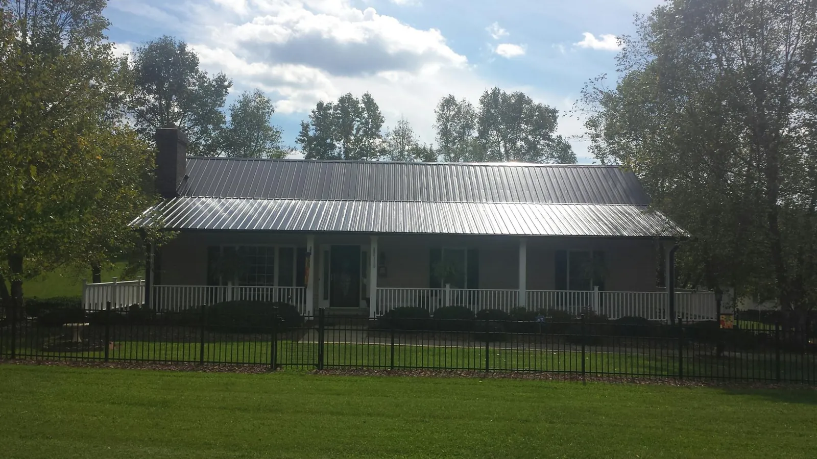 Gray metal roof on a brick ranch with a full width front porch — Gutter Guard Installation work by our crew in Goose Lake