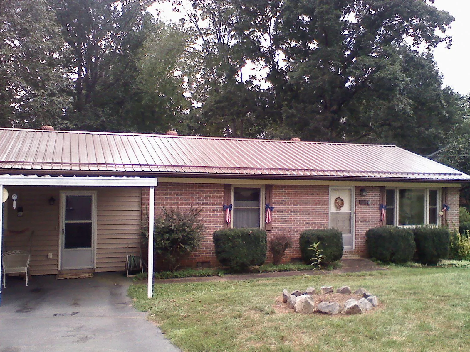 Bronze metal roof and carport on a brick ranch home — Roof Repair work by our crew in Goose Lake