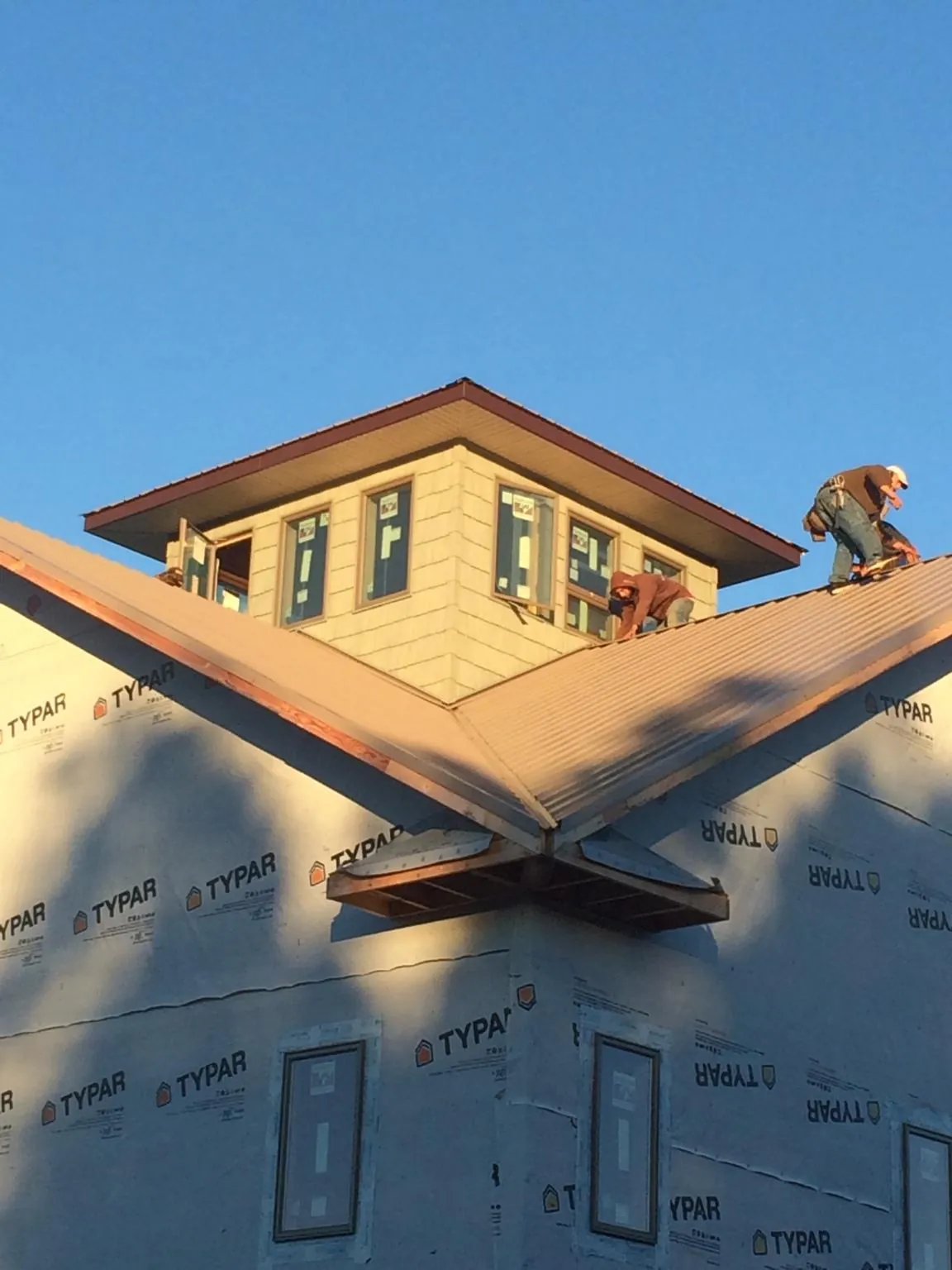 Roofers working around a rooftop cupola on a new metal roof at sunset — Roof Waterproofing in Goose Lake by Roofing Brothers
